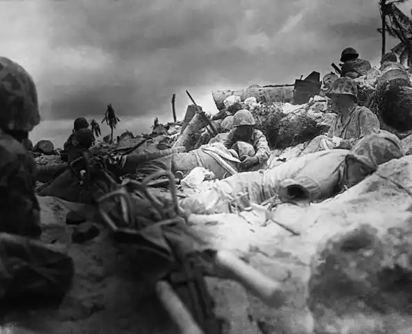 Marines seek cover among the dead and wounded behind the sea wall on Red Beach 3, Tarawa.